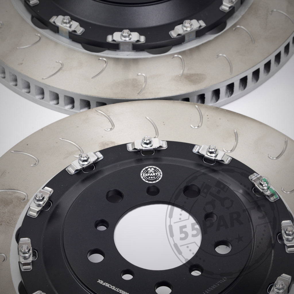 Nahaufnahme von zwei belüfteten und geschlitzten Bremsscheiben mit schwarzen Mitten und Metallbeschlägen aus dem 55Parts-Special: AP Racing Big Brake Kit – Umrüstkit auf Aftermarket-Reibringe.