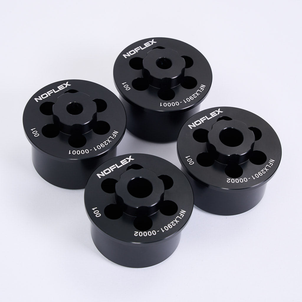 Vier schwarze zylindrische NoFlex Aluminium Tonnenlager von 55Parts, jeweils mit eingeätzten Teilenummern, als Hinterachslager für BMW 3er E46, Z4 E85/E86/E89 und X3 E83, dargestellt auf einer weißen Fläche.