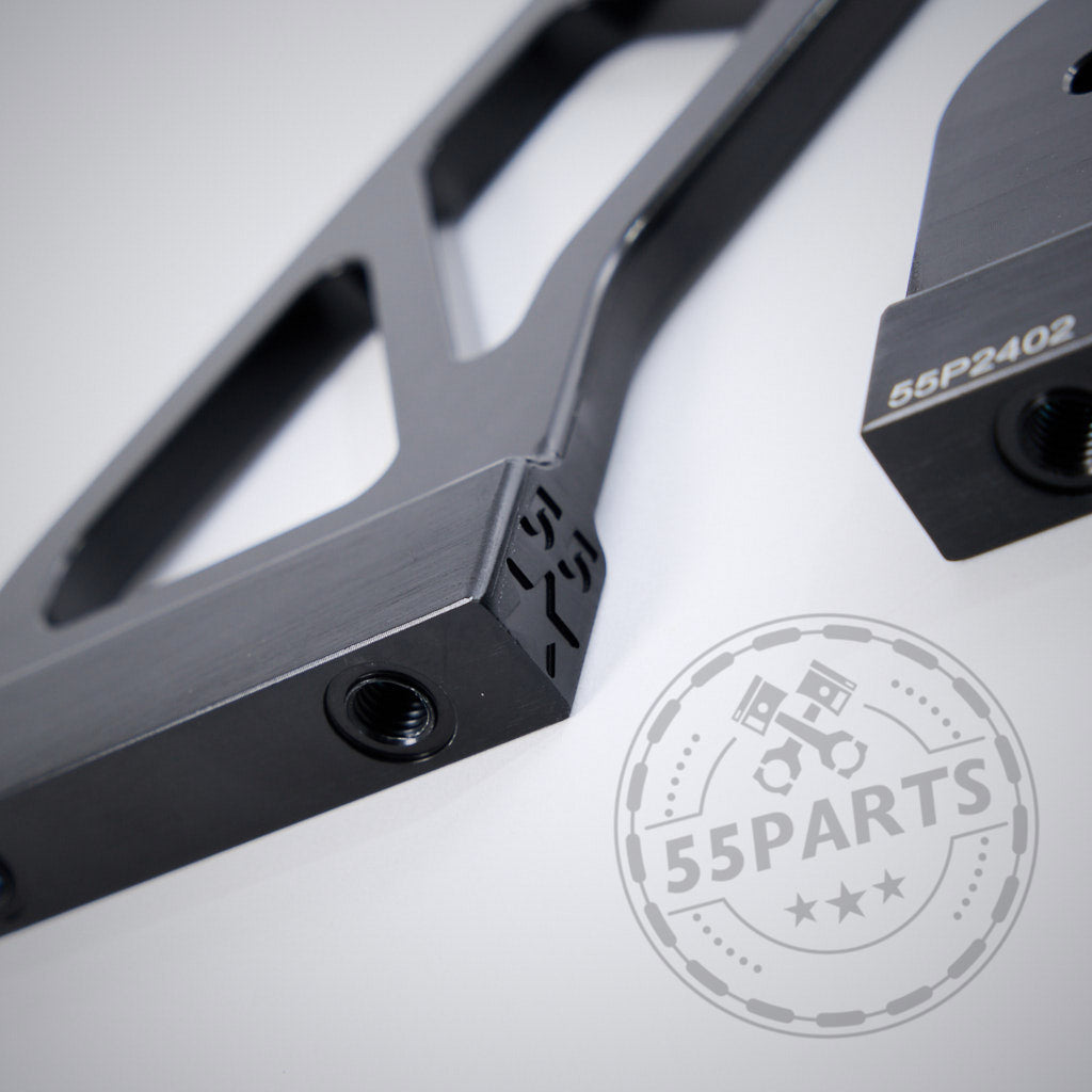 Nahaufnahme zweier schwarzer Metallteile mit Gewindelöchern und eingravierten Codes, im Vordergrund der 55Parts GT4 Carbon Heckspoiler Motorsport inkl. Teilegutachten, passend für fast alle BMW Modelle. Teilegutachten, passend für fast alle BMW Modelle, im Vordergrund.