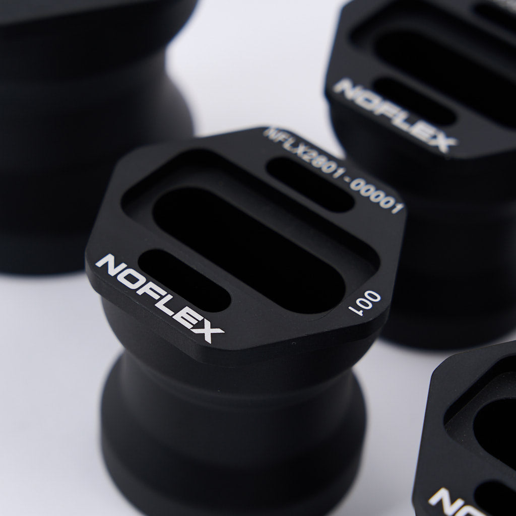 Nahaufnahme der schwarzen 55Parts NoFlex-Lager: Differentiallager (mit Höherlegung), Metall-Diff-Halterungen mit rechteckigen Schlitzen und weißen Markierungen, passend für BMW F8x/G8x M2, M3, M4.