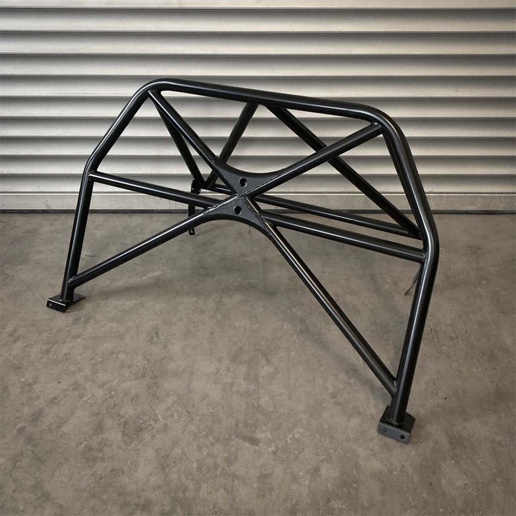 Der Teutscher Clubsportbügel für BMW E81, E82 inkl. Materialzertifikat steht auf Betonboden vor einer geriffelten Metallwand.