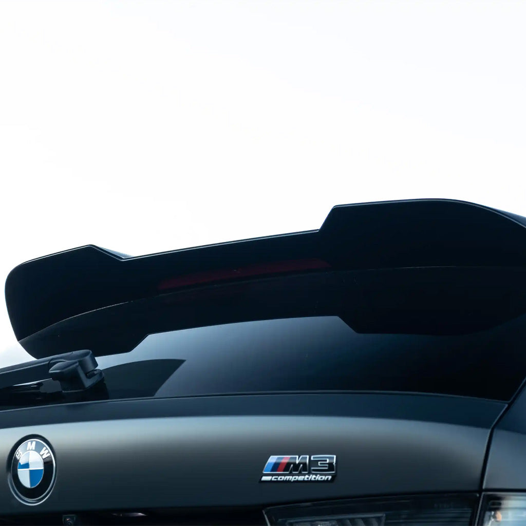 Nahaufnahme eines schwarzen BMW M3 mit dem ZAERO Design EVO-S Heckspoiler für BMW M3 G81 und G21, auf dem das ZAERO-Logo vor einem hellen Himmel zu sehen ist.
