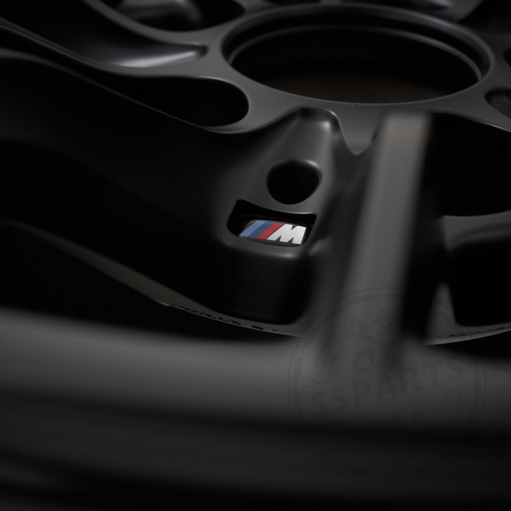 Nahaufnahme einer BMW Motorsport M2 CS Racing Felge 10,5x18 ET46 5x120 Leichtmetallfelge mit roten, blauen und hellblauen M-Logo-Akzenten, die den typischen BMW Motorsport-Stil zur Schau stellt.