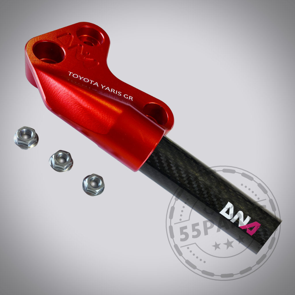 DNA Racing Carbon Domstrebe vorne, passend für Toyota Yaris GR, mit drei Muttern auf hellem Hintergrund. Perfekt für Fahrwerk-Upgrades oder als hochwertiges Tuning Shop Teil von DNA Racing.