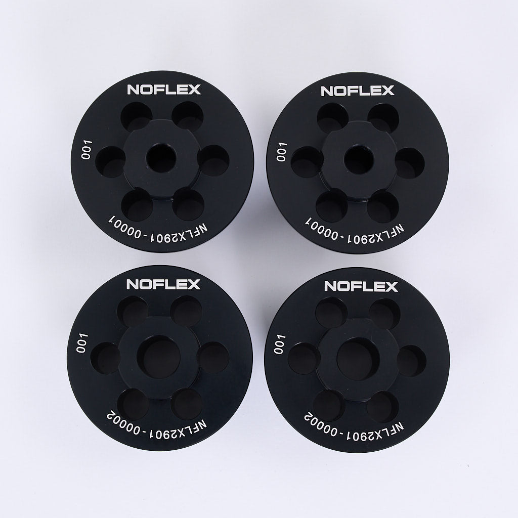 Vier schwarze runde NoFlex Aluminium Tonnenlager von 55Parts, jeweils mit Löchern und weißen Codes, sind in einem 2x2 Raster dargestellt. Passend für BMW 3er E46, Z4 E85/E86/E89, und X3 E83 Hinterachse (Hinterachslager).
