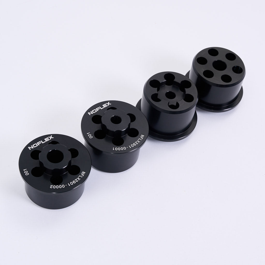 Vier schwarze NoFlex-Lager von 55Parts-Aluminium Tonnenlager Hinterachslager für BMW 3er E46, Z4 E85/E86/E89 & X3 E83 sind in einer Reihe dargestellt, jeweils zylindrisch mit mehreren Löchern, auf weißem Hintergrund.