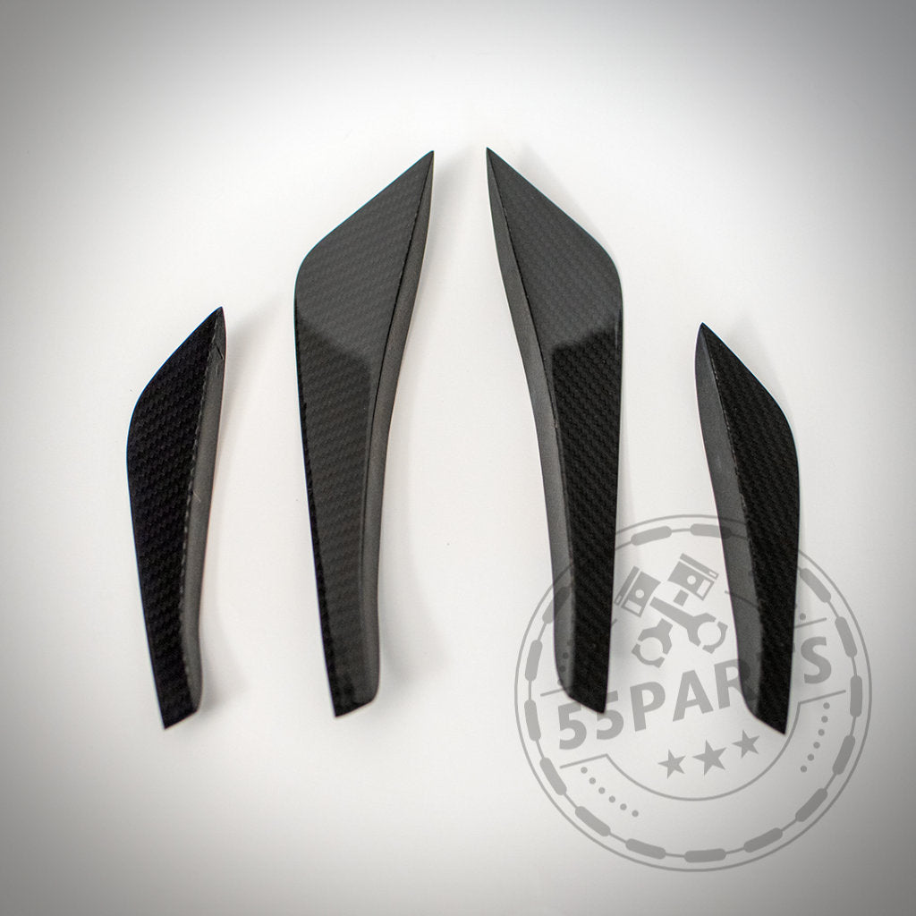 Vier 55Parts Echtcarbon Canards passend für BMW F82/F83 M4 &amp; M4 CS, hergestellt aus echter Kohlefaser, dargestellt auf einer weißen Oberfläche mit einem schwachen Logo-Wasserzeichen.