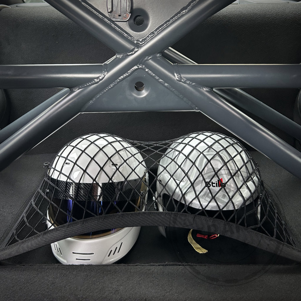 Zwei durch ein Netz gesicherte Helme im Fond eines BMW F-Series mit 55Parts Exclusive Clubsport Innenraum Ausbau inkl. Helmfach, Schalensitze, und sichtbarem Clubsportbügel Überrollkäfig.