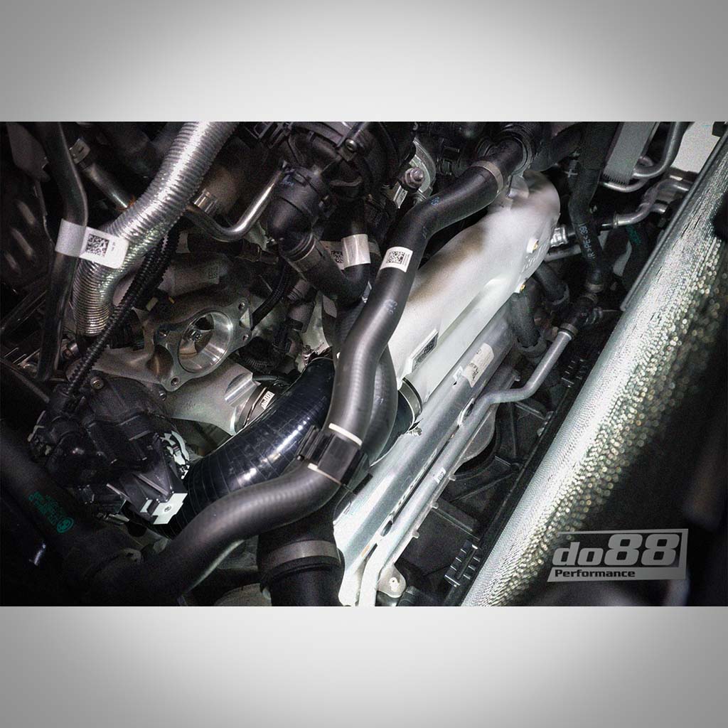 Nahaufnahme von Motorteilen und Schläuchen, mit einem do88 Aluminium-Laderohr für BMW G87 M2/M3/M4/X3M/X4M S58, mit dem do88 Performance Logo in der unteren rechten Ecke.