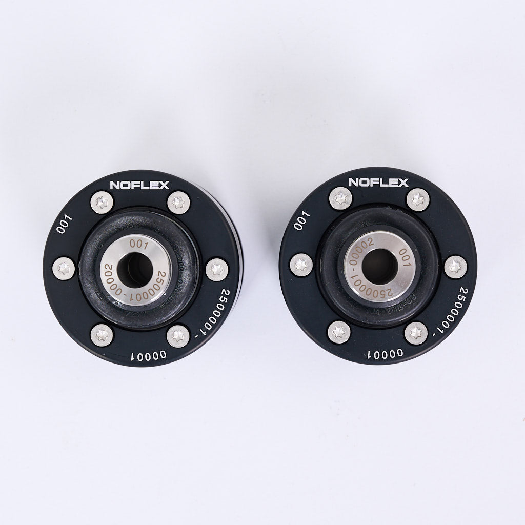 Zwei schwarze, kreisförmige NoFlex-Lager von 55Parts mit Schrauben und nummerierten Etiketten, von oben gesehen - für Uniball Querlenkerlager (hinten) auf der MQB-Plattform: Golf 7, A3, Audi TT, Leon 5F.