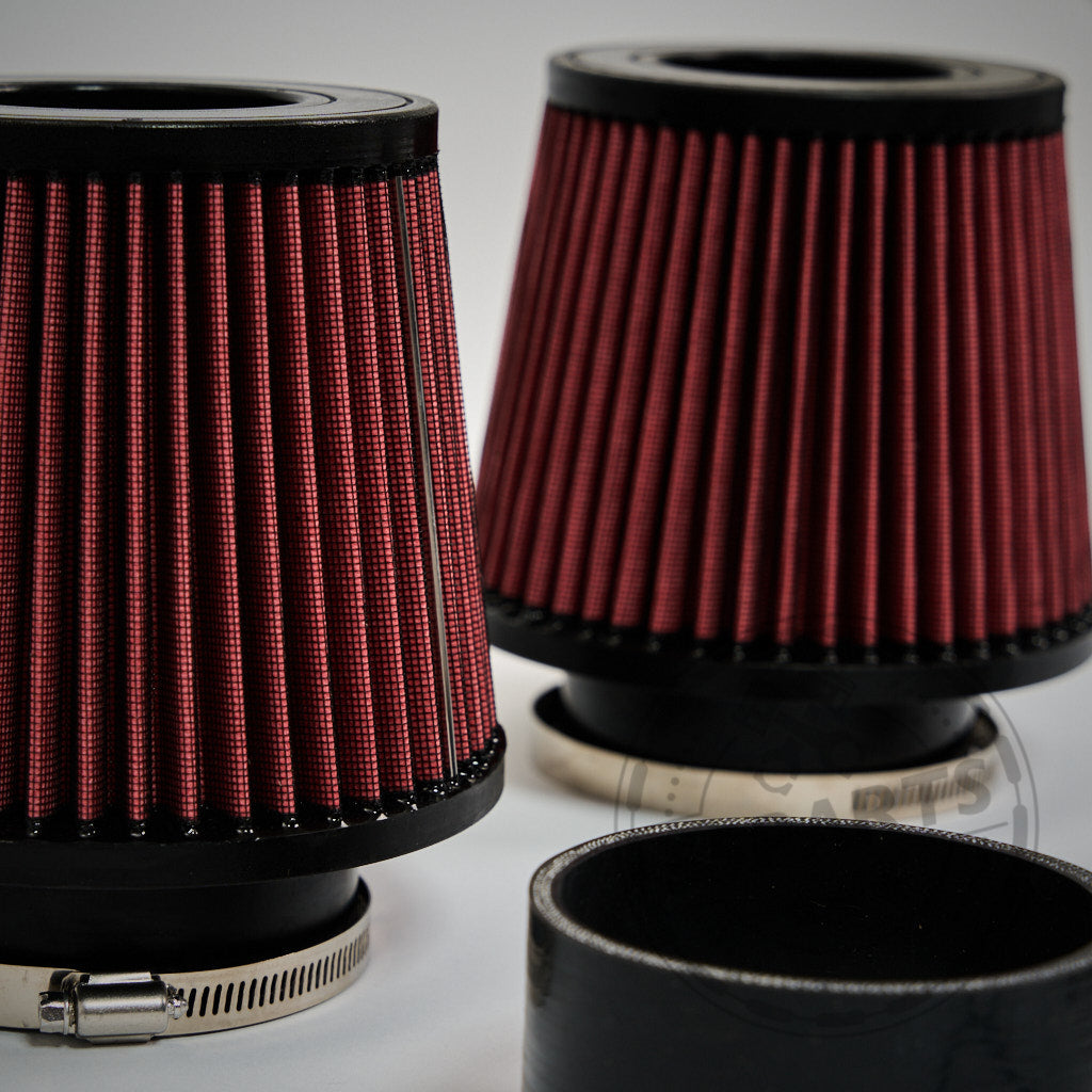 Nahaufnahme von 55Parts Offene Ansaugung Dual Cone Intake Luftfilter für BMW G87 M2, G80/G81 M3, G82/G83 M4 S58, mit roten Kegeln mit schwarzem Sockel und Metallklammern auf weißem Hintergrund. INKL. TEILEGUTACHTEN.