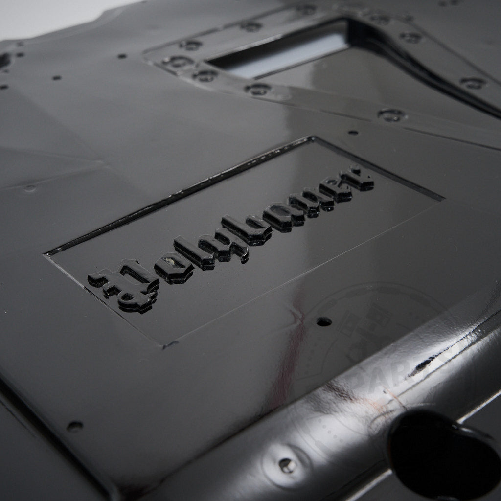 Nahaufnahme eines glänzend schwarzen GFK-Unterbodens inkl. Differential- und Getriebekühlung &amp; Polybauer Automotive, entworfen für Toyota GR Yaris, geprägt mit Jellylayer im gotischen Schriftzug.