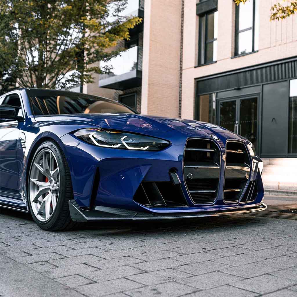 Ein blauer BMW M3 mit einem Twistnfix TNF+ CSL-Style Frontspoiler Carbon ist auf einer Straße in der Nähe von modernen Gebäuden und Bäumen geparkt.