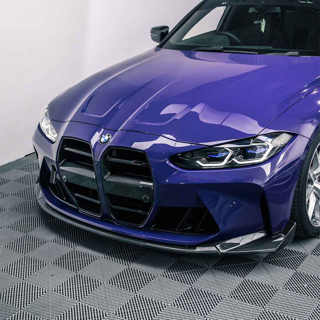 Ein lilafarbener BMW M3 mit einem Twistnfix TNF+ CSL-Style Frontspoiler Carbon ist in einem Innenraum auf einem gemusterten Boden geparkt, der einen großen Frontgrill aufweist.