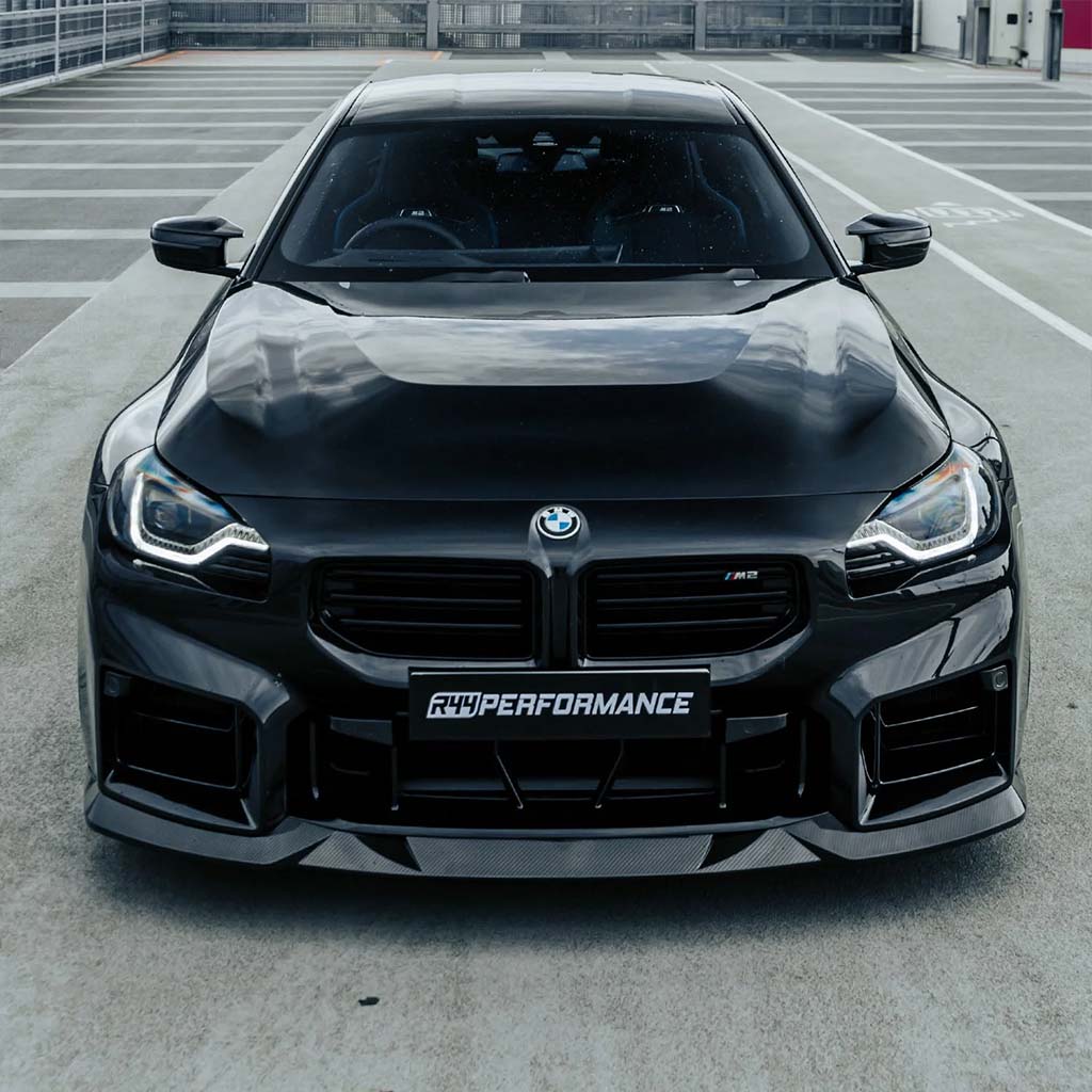 Der Twistnfix MHC TNF+ Edition 1 Frontspoiler Carbon für BMW M2 (G87) hat rote Akzente, ist aus vorimprägnierter Kohlefaser gefertigt und wird auf weißem Hintergrund gezeigt.