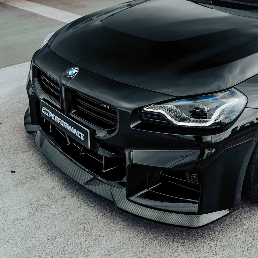 Nahaufnahme der Front eines schwarzen BMW M2 (G87) mit einem Twistnfix MHC TNF+ Edition 1 Frontspoiler Carbon, inklusive Teilgutachten, und einem M Performance Kennzeichen.