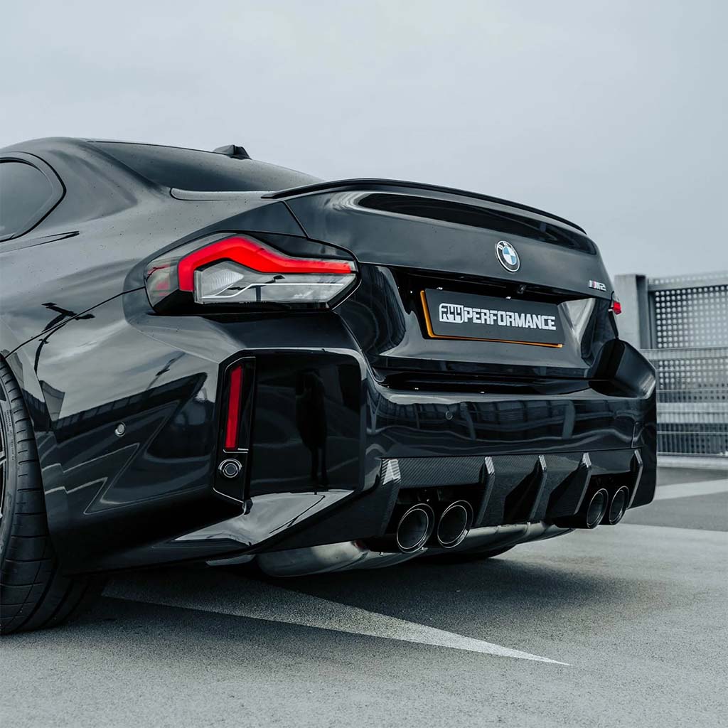 Ein schwarzer BMW M2 (G87) mit sichtbaren Vierfachauspuffanlagen und sportlichen Details steht auf einem Dach, das mit dem Twistnfix TNF+ Heckdiffusor Carbon aus Prepreg-Kohlefaser ausgestattet ist und mit Teilegutachten versehen wurde.