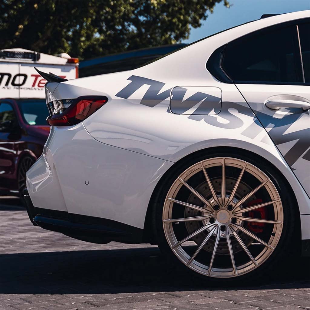 Nahaufnahme eines weißen BMW 3er (G20) mit großen Leichtmetallrädern, OEM-Plus-Design und einem TWISTNfix TNF+ PSM Performance Carbon Ducktail.
