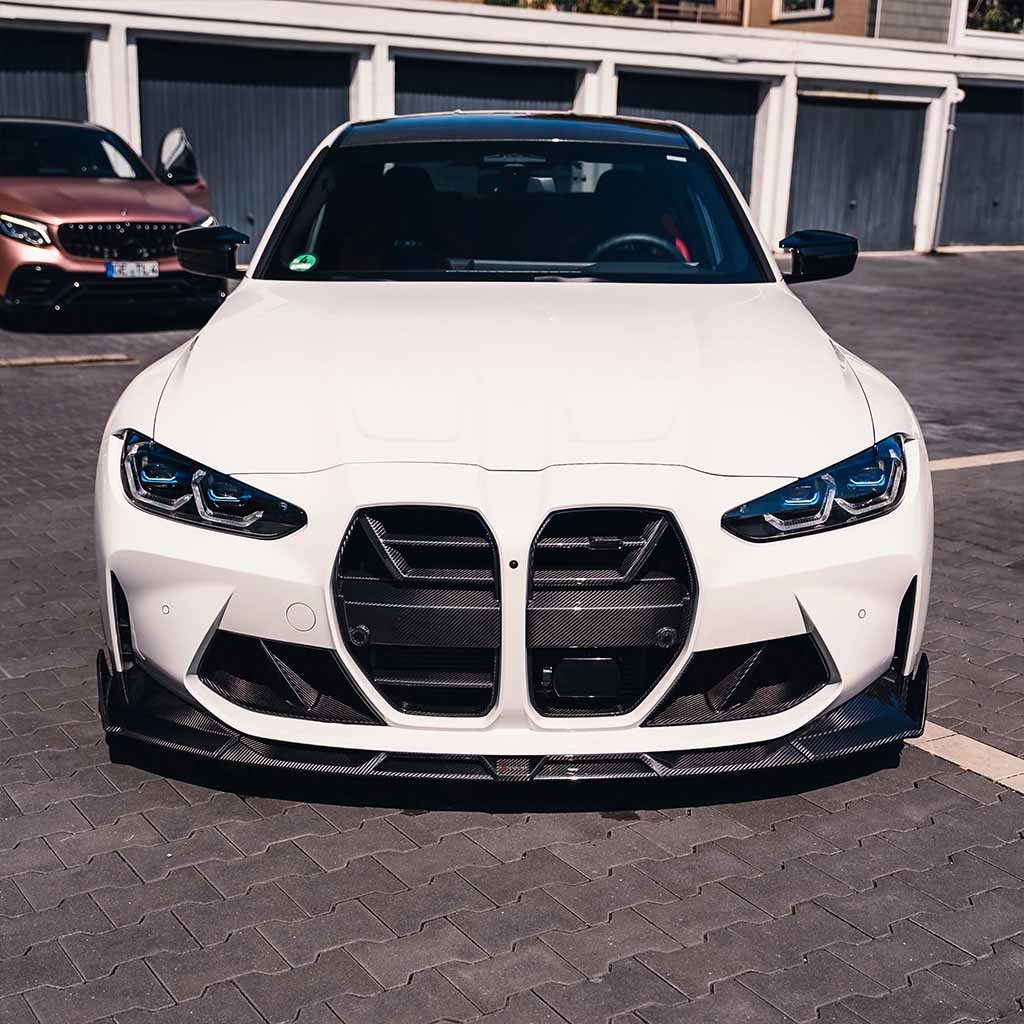 Ein weißer BMW M3 (G80/G81) mit Twistnfix TNF+ Performance Lufteinlässe Carbon ist auf einem Parkplatz geparkt.