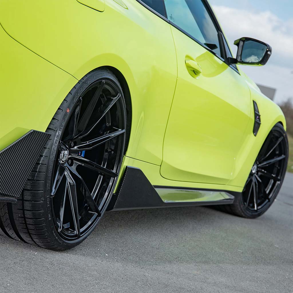 Nahaufnahme eines leuchtend gelben Sportwagens mit schwarzen Felgen und Twistnfix TNF+ Performance Seitenschweller Carbon für BMW M4 (G82/G83), geparkt auf einer Straße.
