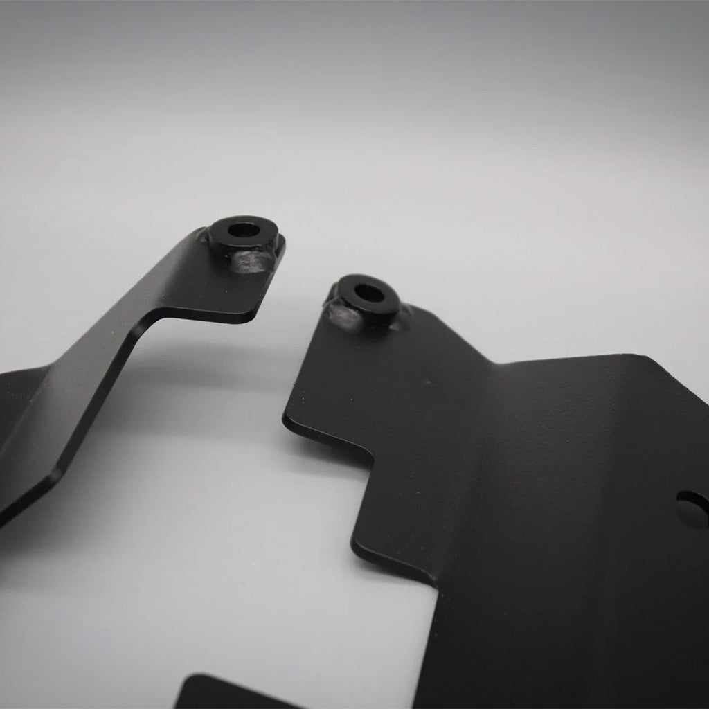 Nahaufnahme von zwei schwarzen Metallbügeln mit abgewinkelten Formen und Befestigungslöchern, kompatibel mit BMW E46/E85/E86 Z4, ideal für Schalensitz Montage. Produkt: Teutscher Recaro/Sparco/OMP Sitzkonsolen inkl.. Materialnachweis.