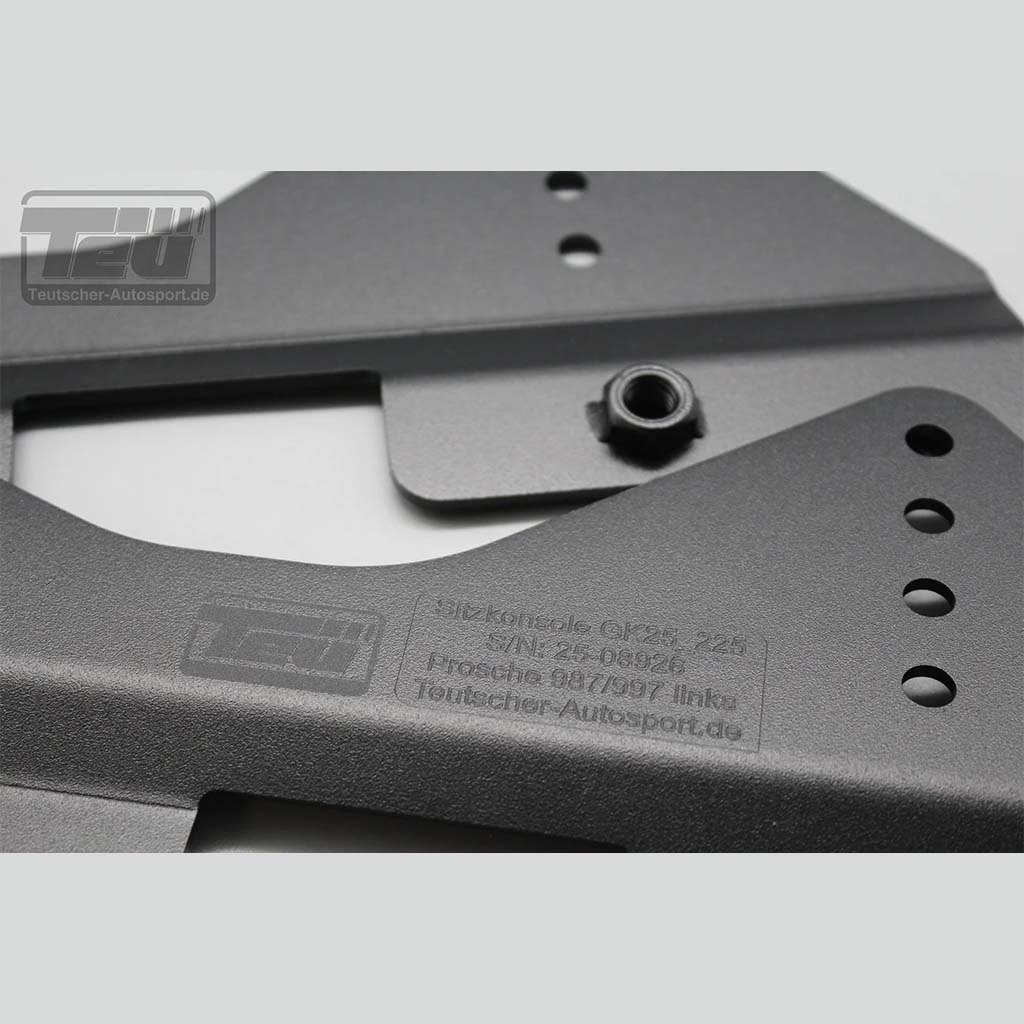 Nahaufnahme eines grauen Metall-Autoteils mit eingraviertem Text und einem schwarzen Bolzen, Logo in der Ecke-ideal für Teutscher Recaro, Sparco, OMP Sitzkonsolen für Porsche 911 997, Boxter 987, Cayman 987C inkl.. Materialnachweis.