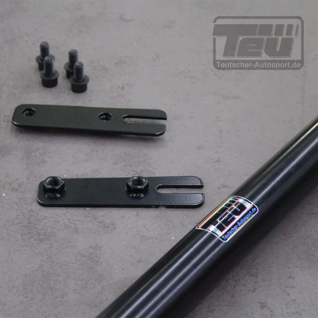 Schwarze Metall Teutscher Trackday Gurtstrebe für 4-Punkt Gurte von 55Parts, mit Befestigungswinkeln und Schrauben, abgebildet auf grauer Oberfläche. Passend für BMW G87 M2, bietet einfache Plug'n'Play Montage und beinhaltet Materialnachweis.