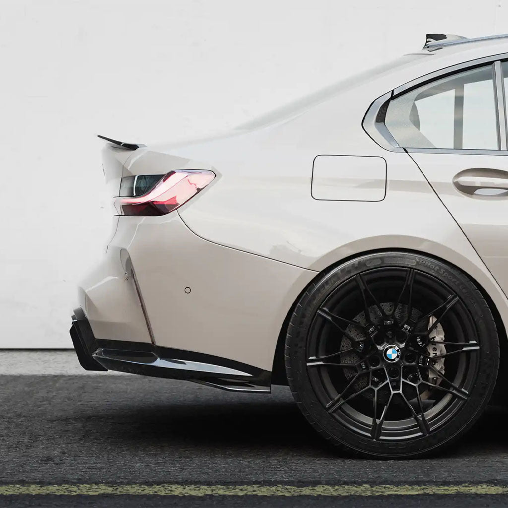 Rückansicht einer beigen BMW-Limousine mit schwarzen Rädern, ausgestattet mit einem ZAERO Design EVO-S Diffusor Erweiterung für BMW M3 G80/G81, geparkt neben einer weißen Wand.