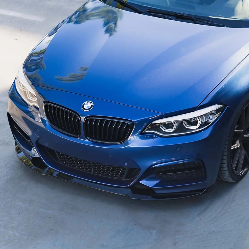 Nahaufnahme der Frontpartie eines blauen BMW F22 mit einer ZAERO Design EVO-1 Frontlippe von ZAERO, geparkt an einem sonnigen Tag.