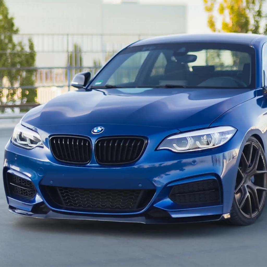 Blauer BMW F22 mit einer ZAERO Design EVO-1 Frontlippe von ZAERO, geparkt im Freien an einem sonnigen Tag, gezeigt von der vorderen linken Seite.