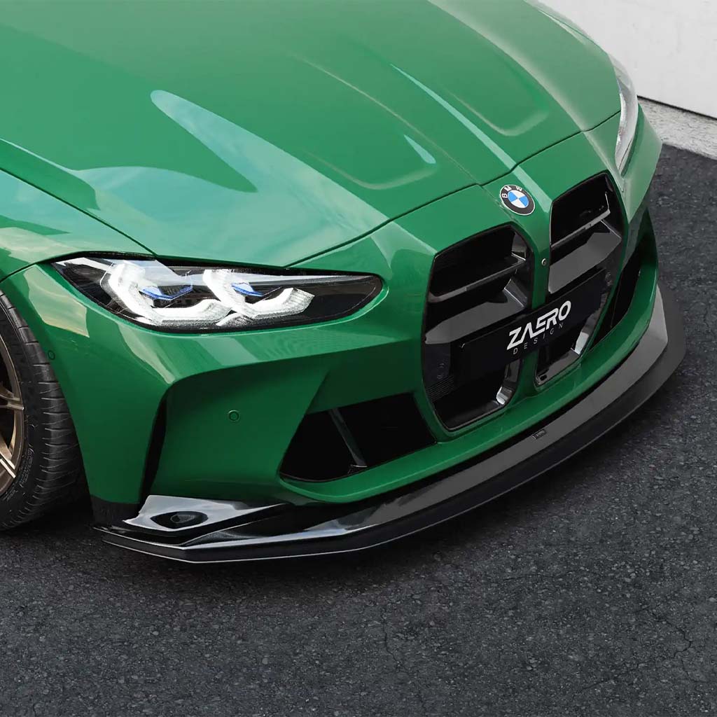 Nahaufnahme eines grünen BMW M3/M4 (G80, G81, G82, G83) mit einem am Fahrwerk montierten ZAERO Design EVO-R Frontsplitter verstellbar von ZAERO, geparkt auf dem Bürgersteig und als Highlight von Motorsport-Performance.