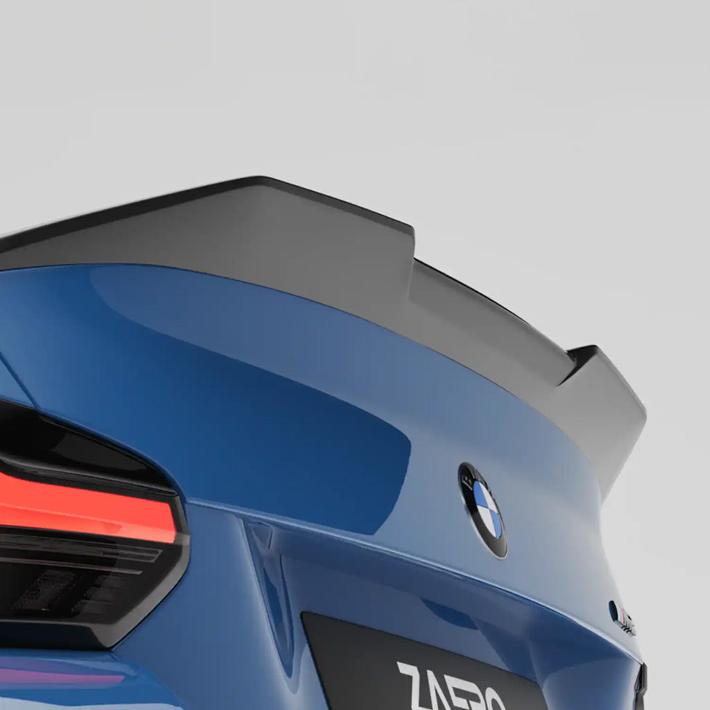 Nahaufnahme eines blauen BMW M2 G87 mit dem ZAERO Design EVO-S Heckspoiler passend für BMW M2 G87 und G42 von ZAERO, der ein leuchtend rotes Rücklicht vor grauem Hintergrund zeigt.