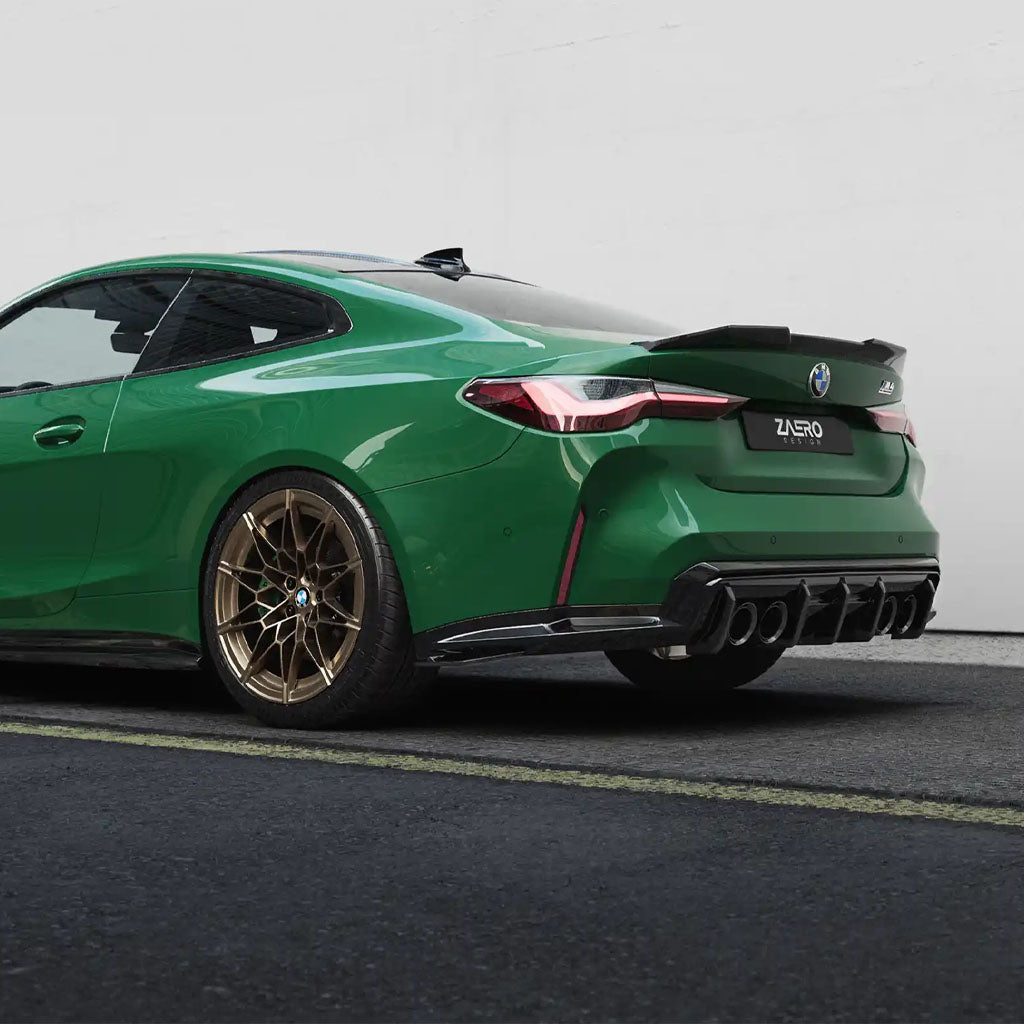 Grüner BMW M4 G82 mit bronzenen Rädern und einem ZAERO Design EVO-S Heckspoiler, auf dem Bürgersteig geparkt und von der hinteren Seite betrachtet.