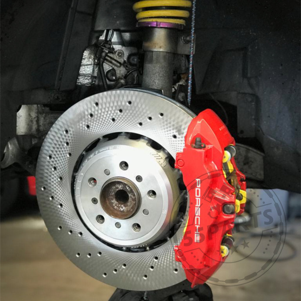 Nahaufnahme eines Epytec Bremssatteladapters für Porsche 997 380x30 Bremsscheibe, dargestellt mit gelochter Scheibe und rotem Bremssattel, passend für BMW E92/E93/E91 M3 4.0 V8 und 1M; gelbe Fahrwerksfeder oben sichtbar.
