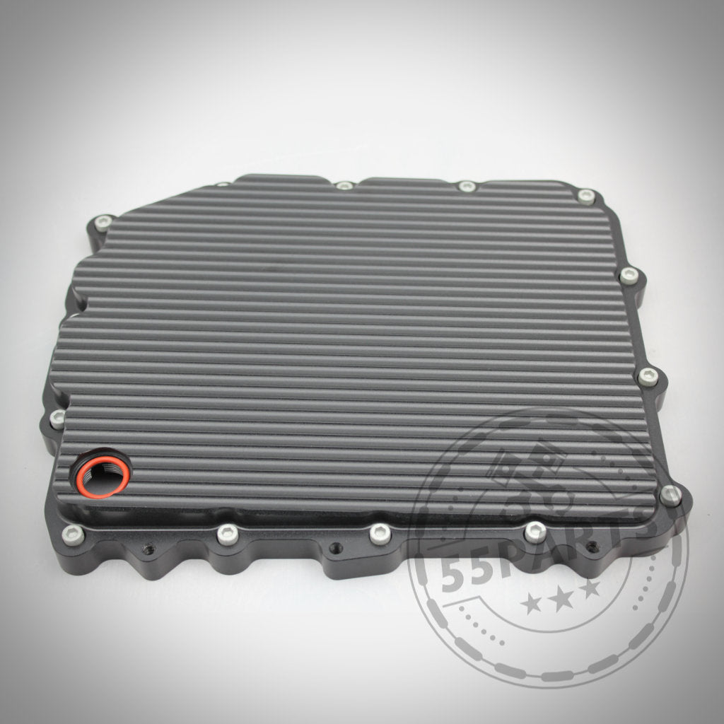 Nahaufnahme einer gerippten, rechteckigen 55Parts Exclusive Aluminium-Ölwanne (DKG GS7D36BG) mit Schrauben am Rand, entworfen passend für BMW 1/335i, M2(c), M3, M4, M5 und M6 E- & F-Serie.