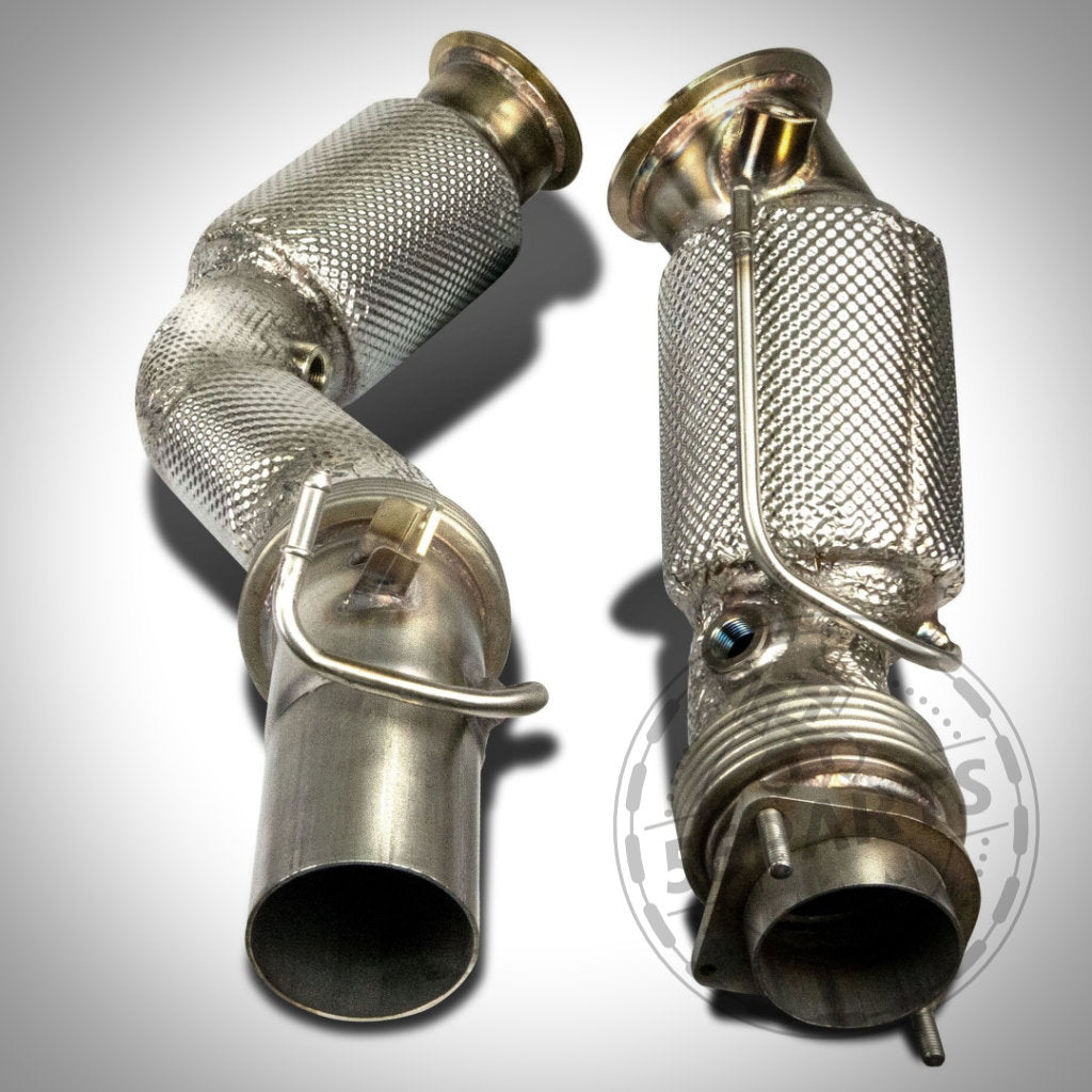 Zwei HJS ECE Downpipes mit 200-cpi HJS Sport-Kat passend für BMW M2 Competition, M2CS, M3 und M4 S55 (mit/ohne OPF) sind mit strukturiertem Hitzeschild und verschweißten Fittings auf hellem Untergrund abgebildet.