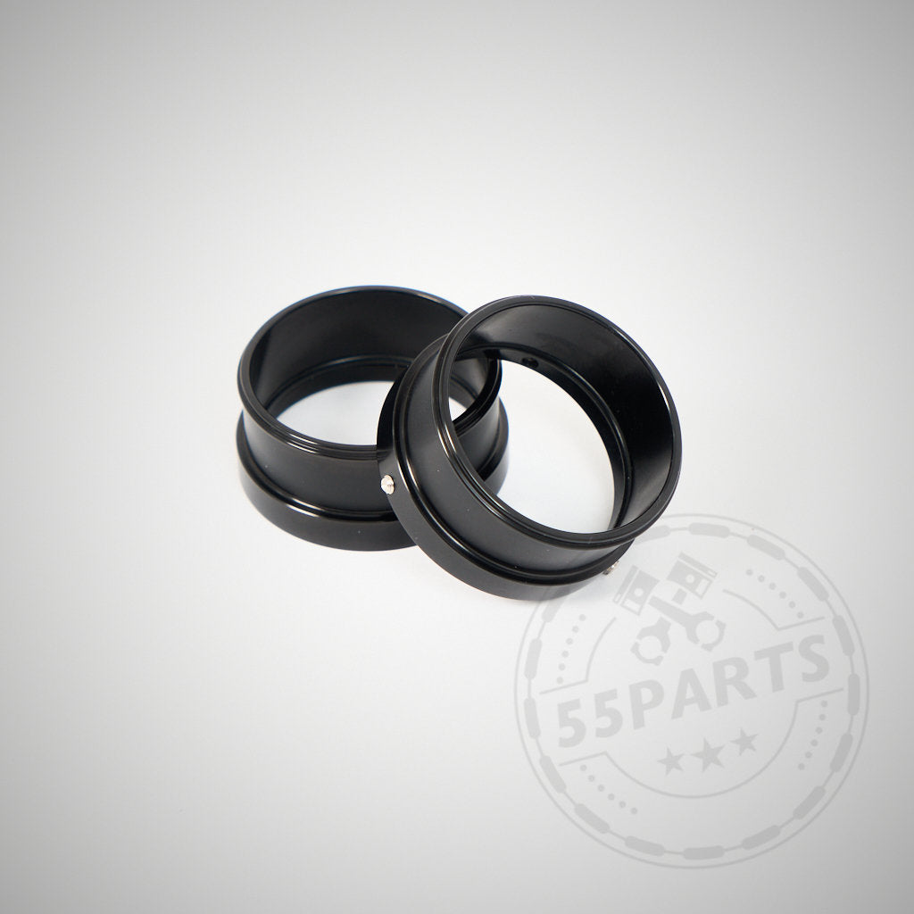 Zwei mattschwarze Metallringe, der 55Parts Spezialadapter zur Montage von 2" Silikoneinlässen an 1,75" Turbos (BMW 135i, 1er M Coupé, 335i(x) N54), sind auf hellgrauem Untergrund gestapelt. Wasserzeichen in der Ecke.