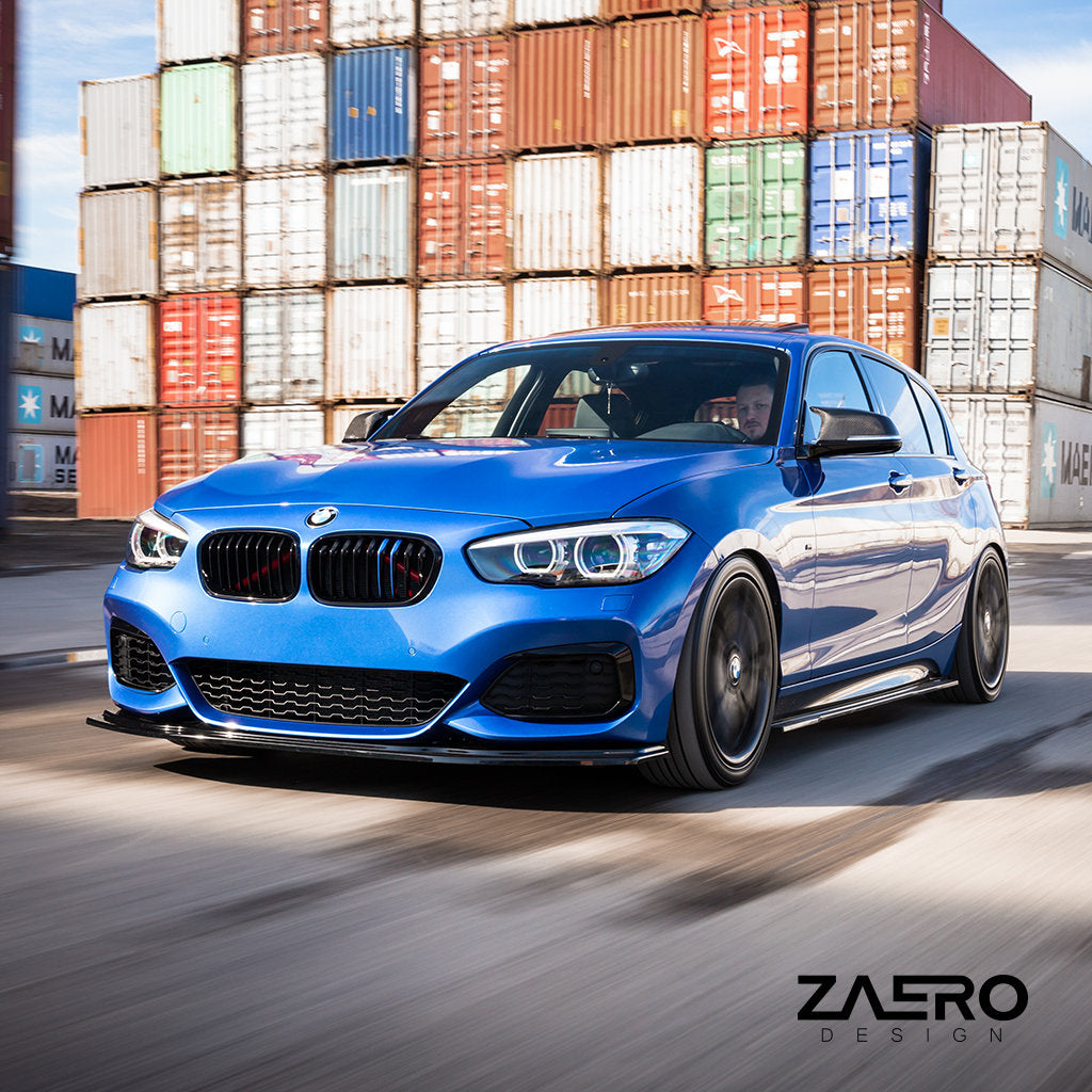 Ein blauer BMW F2x mit einem ZAERO Evo-1 Frontspoiler fährt an gestapelten Schiffscontainern vorbei, das ZAERO-Logo in der Ecke.