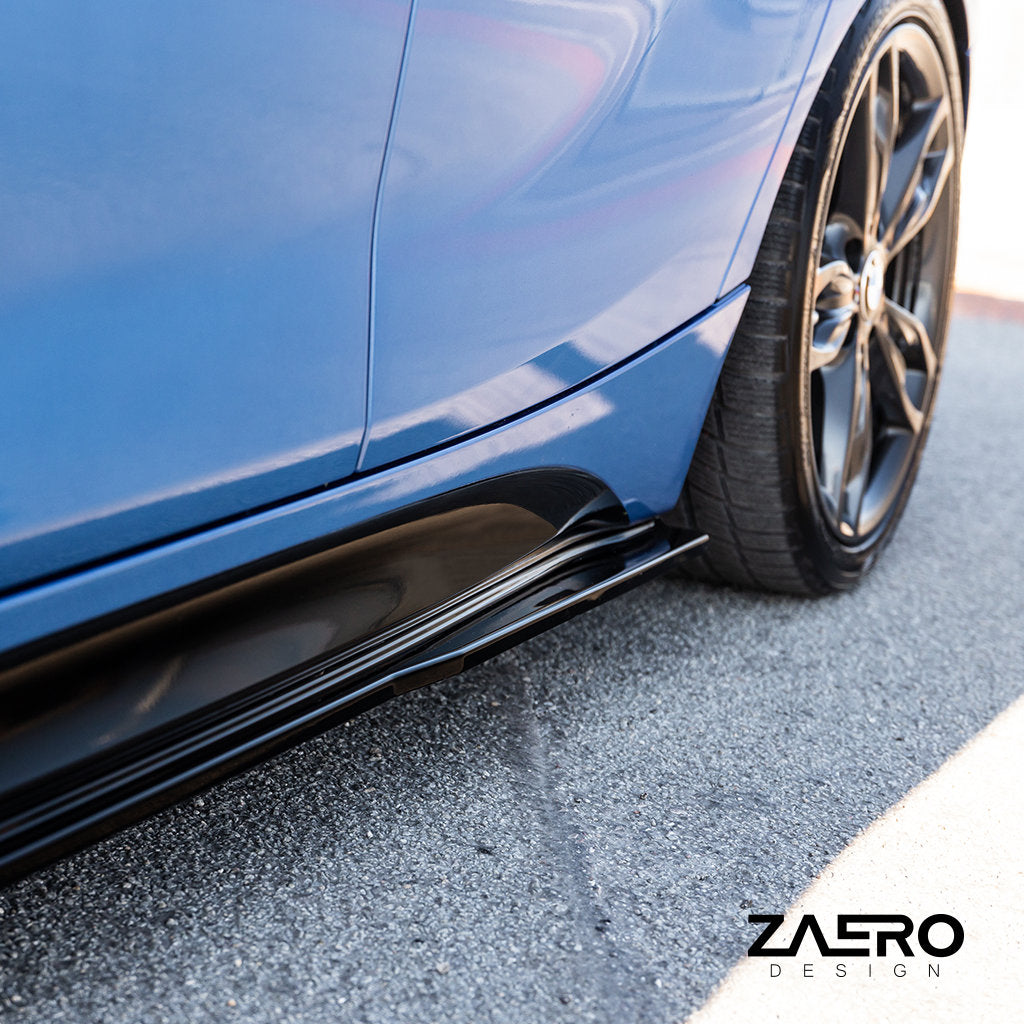 Nahaufnahme eines blauen BMW F2x mit ZAERO Evo-1-Seitenschwellern. Das Hinterrad ist auf einer befestigten Fläche zu sehen. Das ZAERO-Logo erscheint in der Ecke.